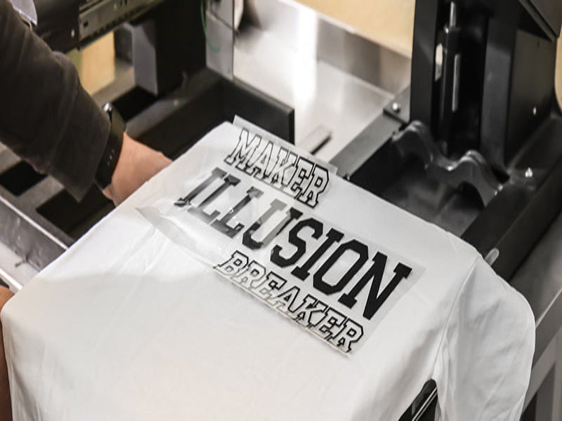 Prozess der Textilveredelung in der Nickifabrik Manufaktur: Manuelles Abziehen einer Transferfolie mit schwarzem Motiv von einem weißen T-Shirt auf einer professionellen Heißtransferpresse.